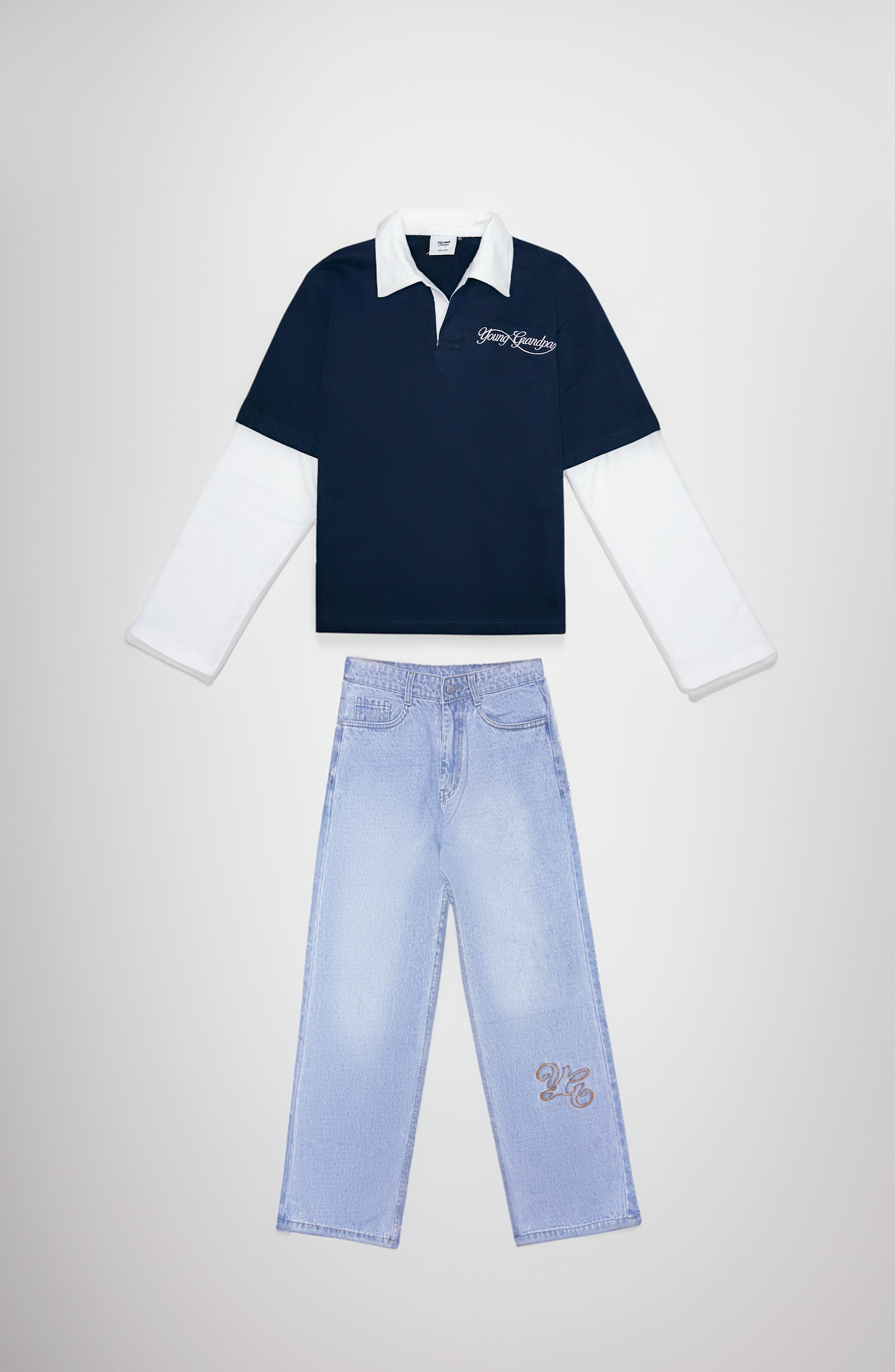 Navy polo shirt with white collar and long-sleeve underneath, paired with light blue jeans on a light gray background.