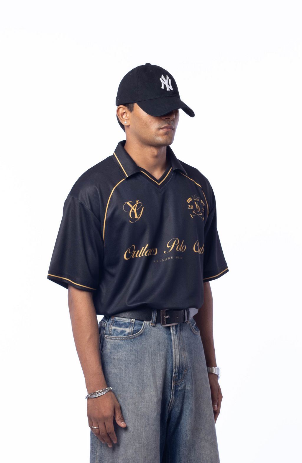 Person wearing a black polo shirt with gold accents and gray jeans on a white background