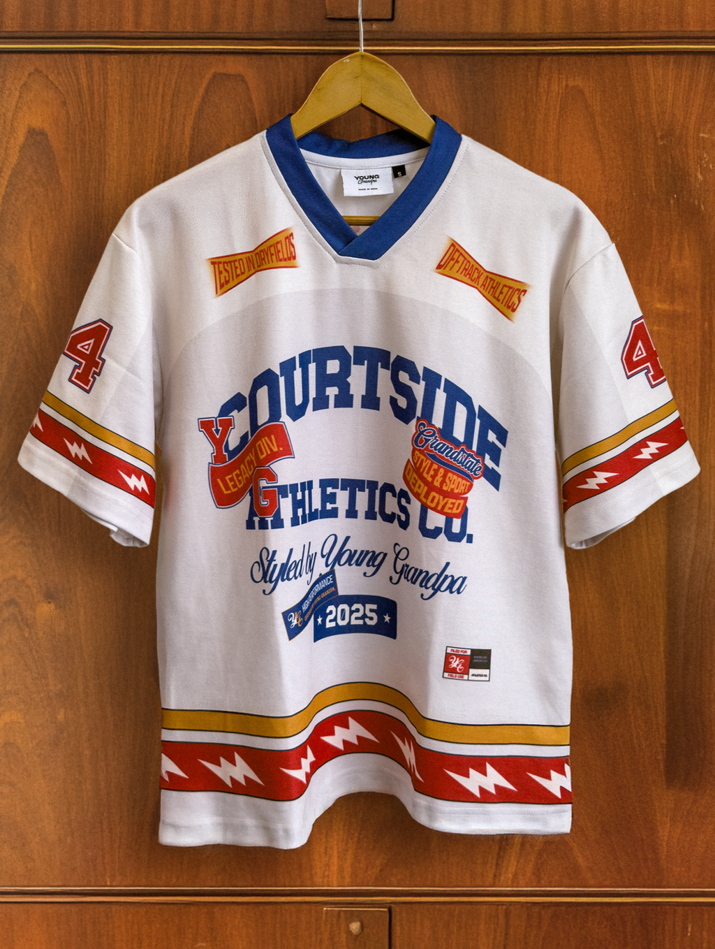 White sports jersey with colorful text and graphics on a wooden wardrobe background
